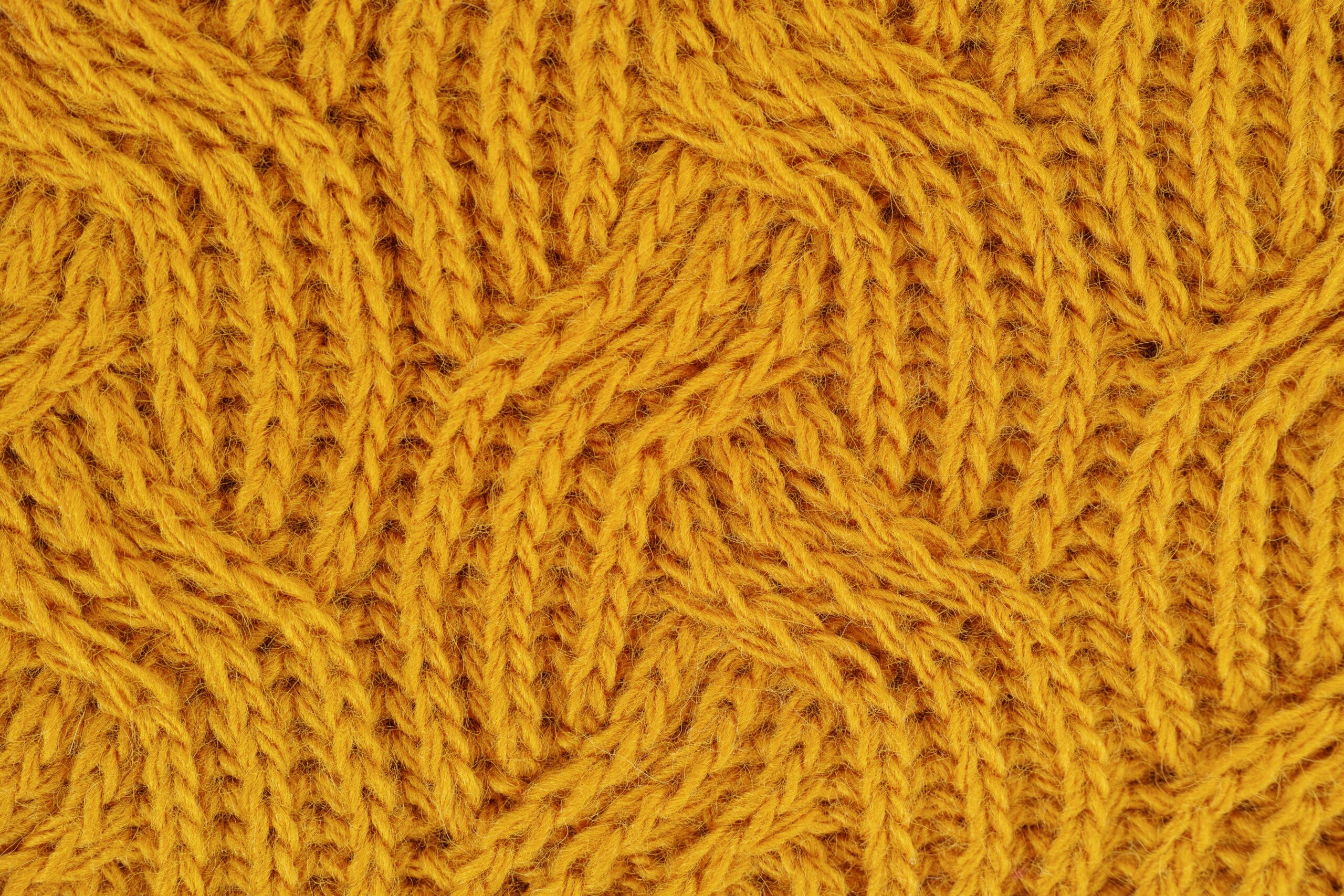 Detailed close-up of a yellow knitted wool pattern, ideal for textile design.